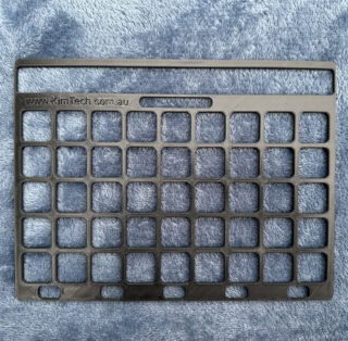 A black keyguard on a grey blanket background.